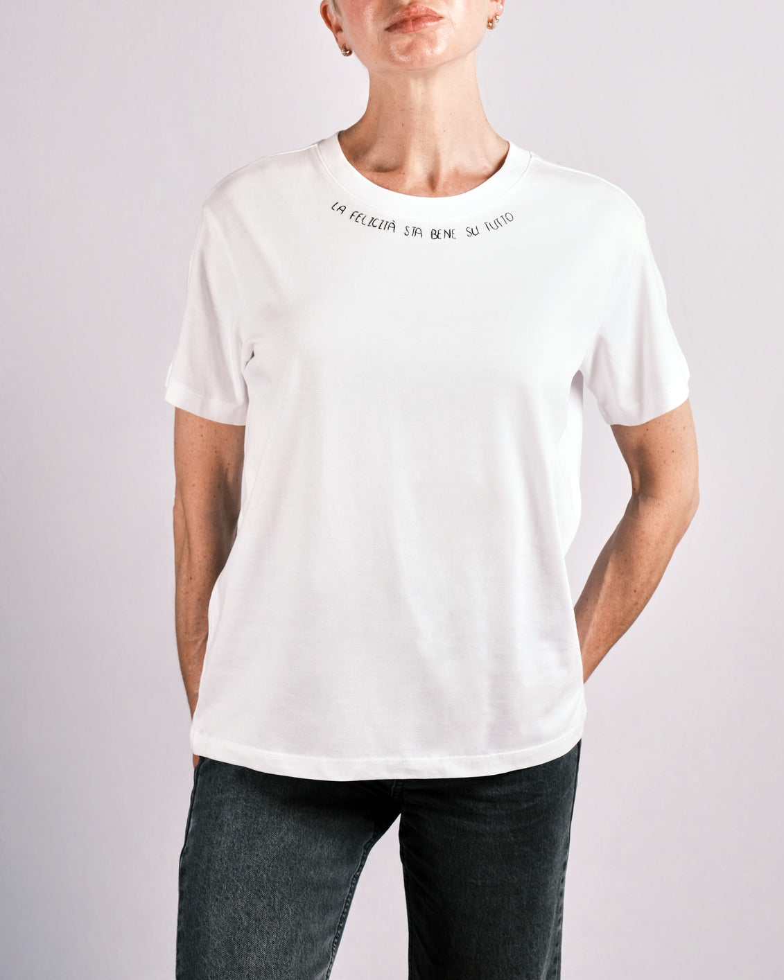 T-shirt “LA FELICITÀ STA BENE SU TUTTO” indossata, la maglietta in 100% cotone è ricamata con la scritta "la felicità sta bene su tutto"